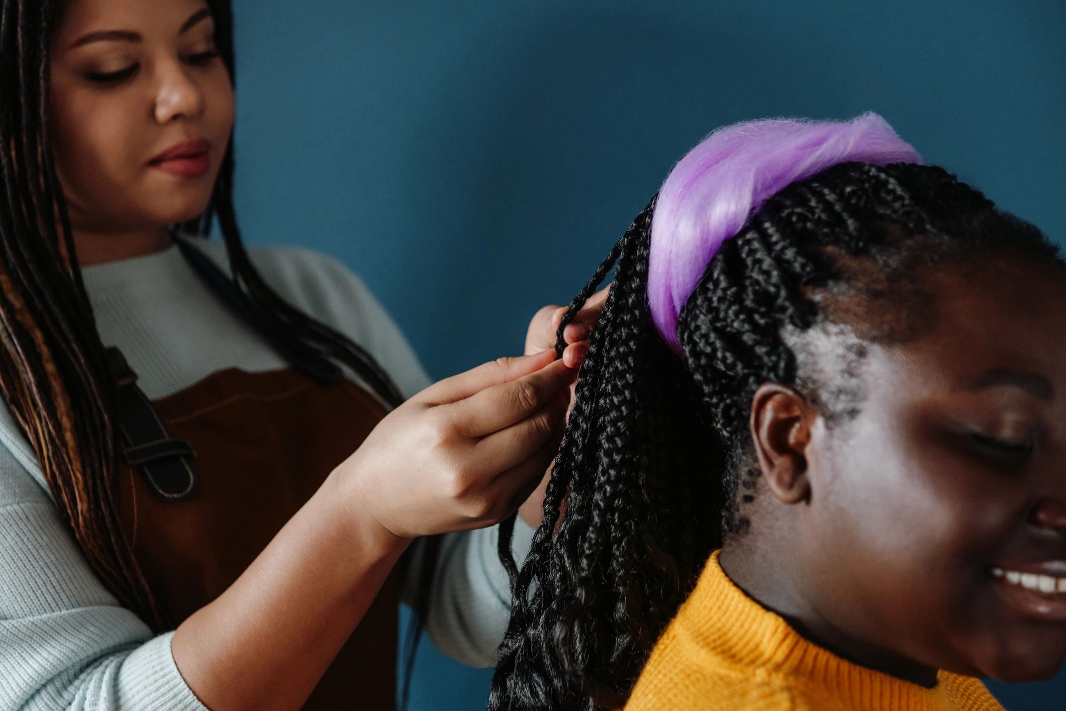 Close-up of confident African hairdresser braiding hair to a customer.